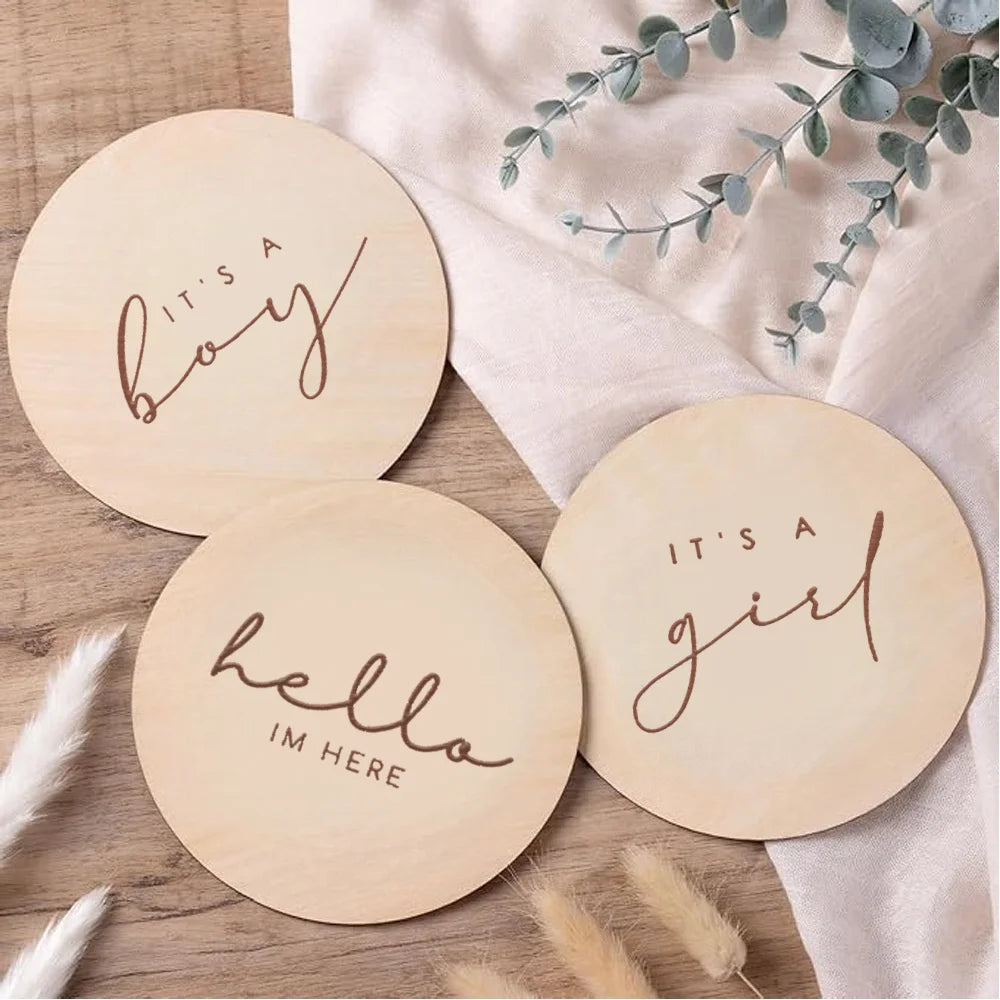A set of natural wood plaques with script text saying It's a boy and It's a girl for gender reveal