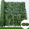 Green artificial ivy hedge fence panels rolled up and laid out, showing dense foliage.