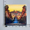 A magnet featuring a panoramic view of the Los Angeles skyline with palm trees and hills under a sunset sky.