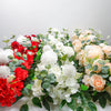 A lush arrangement of white and peach artificial roses and greenery for event decor.