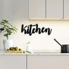 Black script wall art spelling kitchen on a white kitchen backsplash