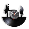 A black vintage vinyl record wall clock featuring silhouettes of a person and a bird on a record platter.