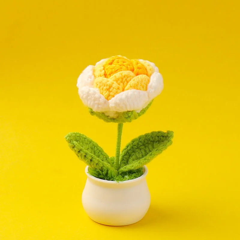 A hand woven crochet flower in yellow and white is potted in a small white ceramic cup against a yellow background.