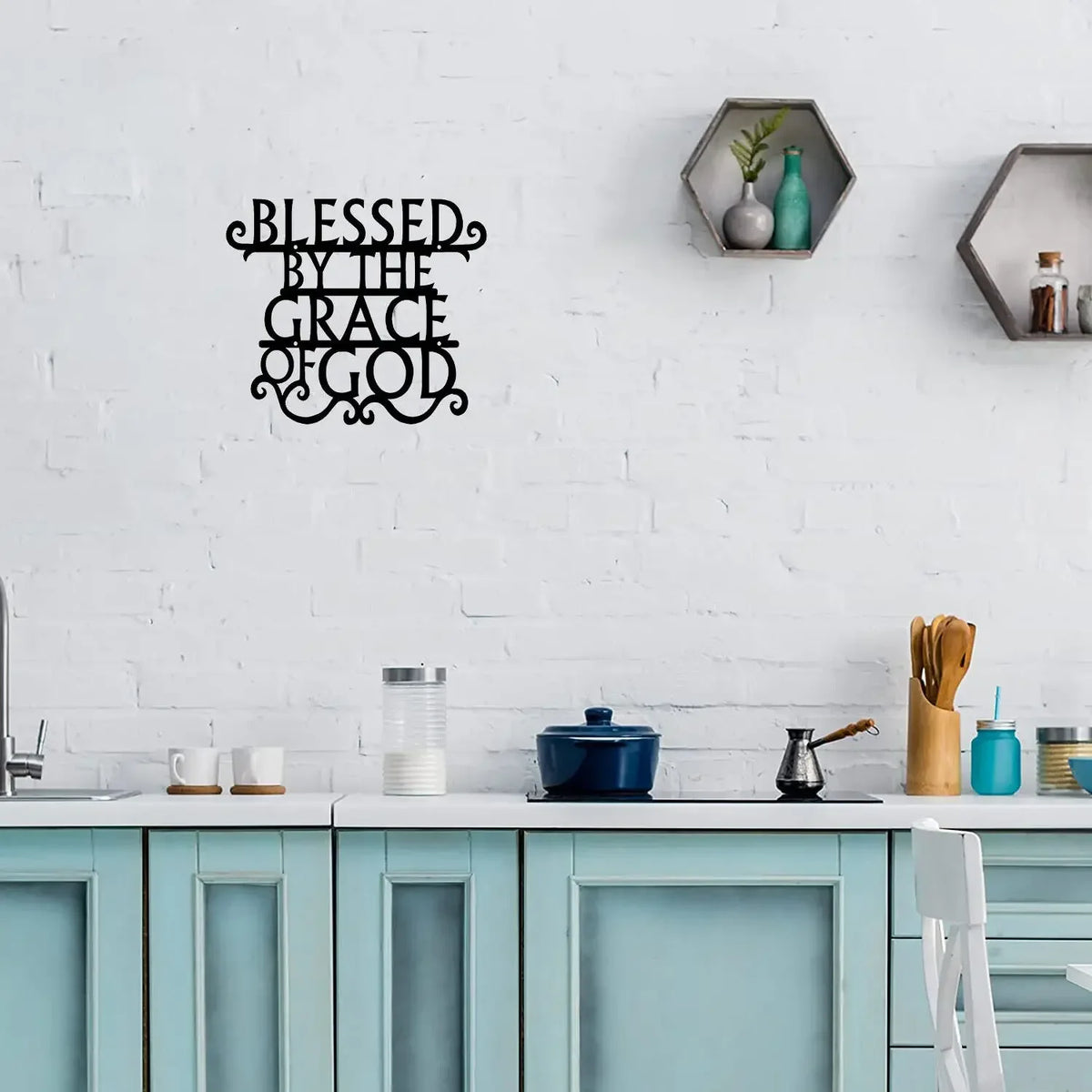 Black metal wall art sign with the text Blessed by The Grace of God displayed on a white brick wall.