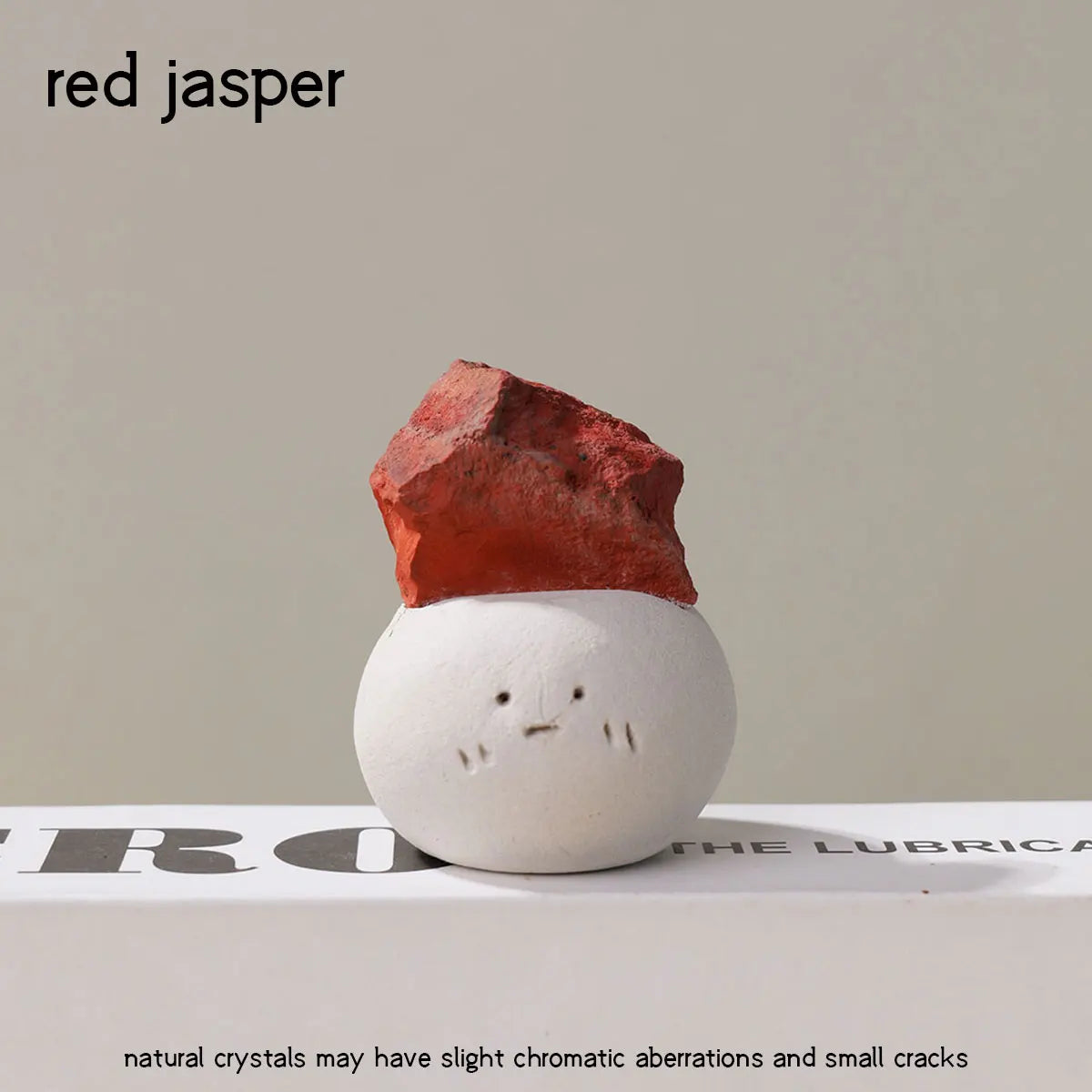 A reddish-orange jasper stone shaped like a bean resting on a white surface.