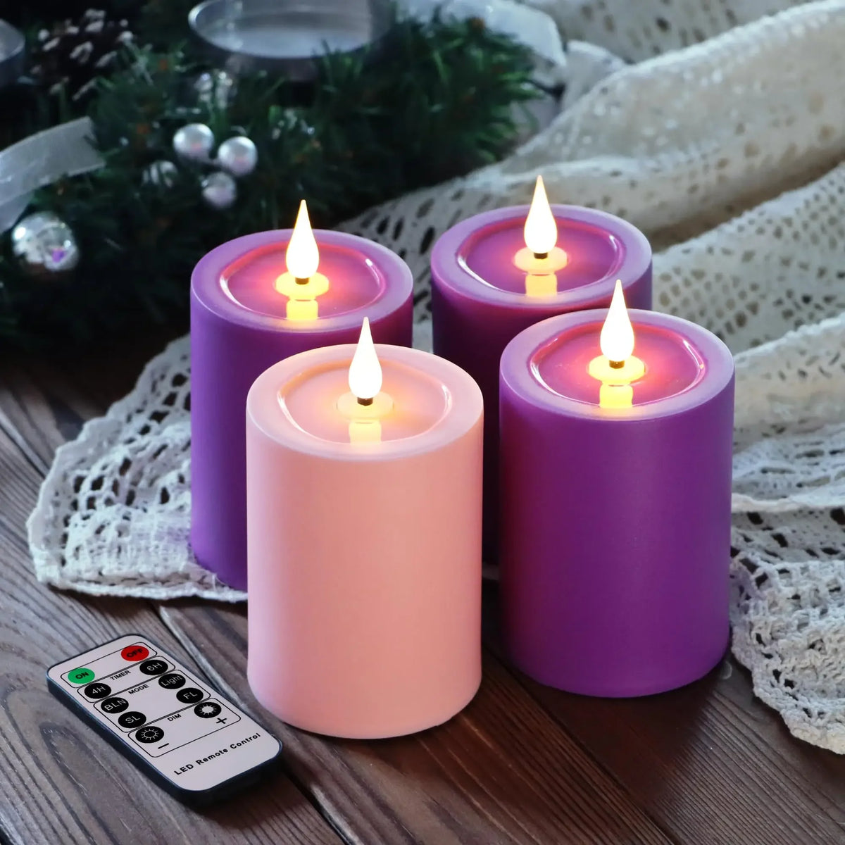 Purple and pink flameless LED candles sitting on a wooden surface next to a remote control.