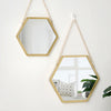 A gold-framed hexagon decorative wall mirror hanging on a white wall.