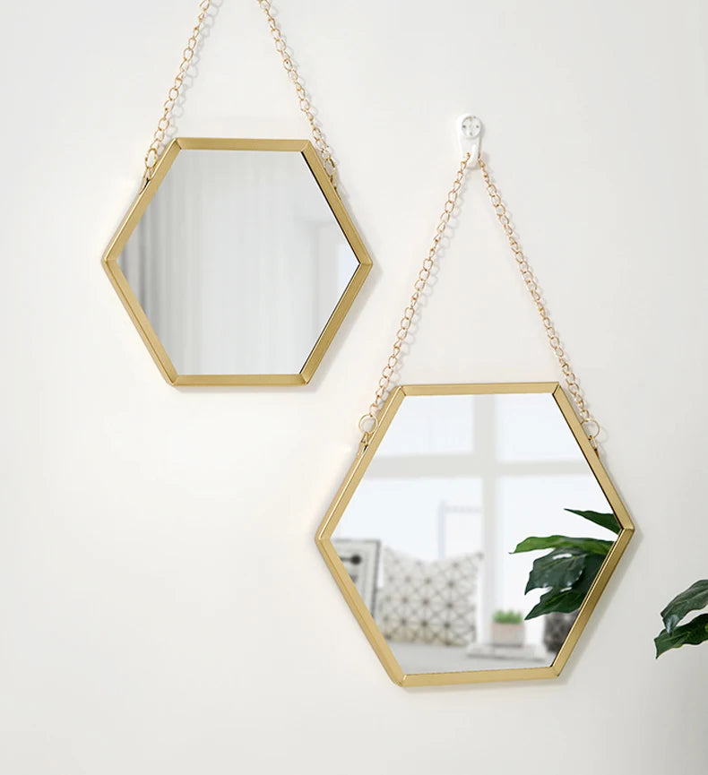 A gold-framed hexagon decorative wall mirror hanging on a white wall.