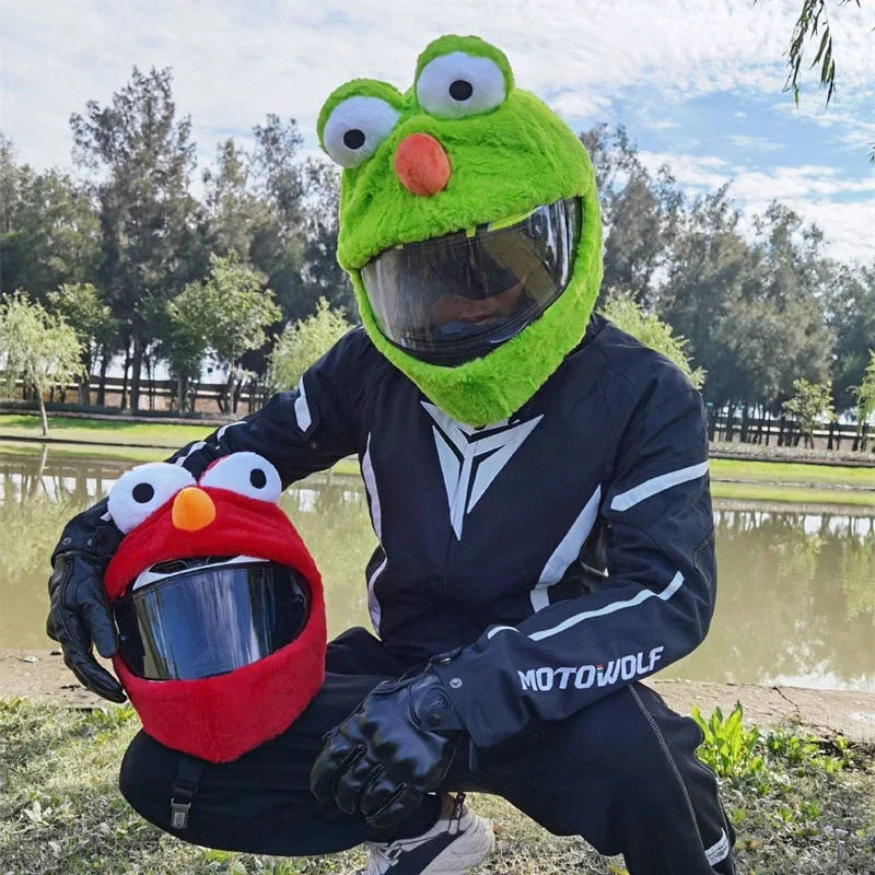A person wearing a green cartoon plush helmet cover for a full-face motorcycle helmet outdoors.