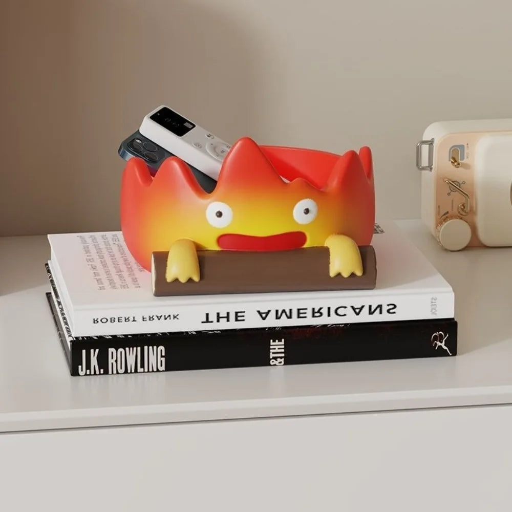 An anime-inspired orange fire spirit resin key tray and desk organizer resting on a stack of books.