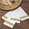 White paper dinner napkins with rose gold trim and intricate scrollwork displayed on a wooden surface.