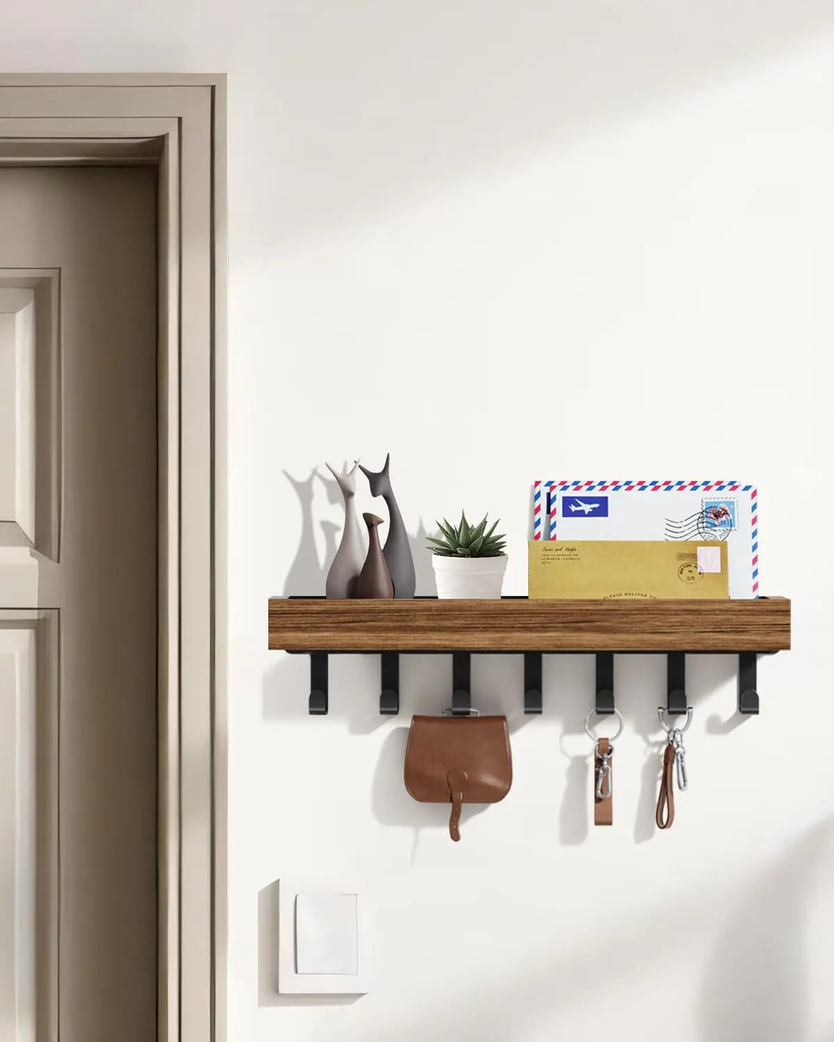 A rustic wooden floating shelf with hooks mounted on a white wall, displaying decorative figurines and cards.