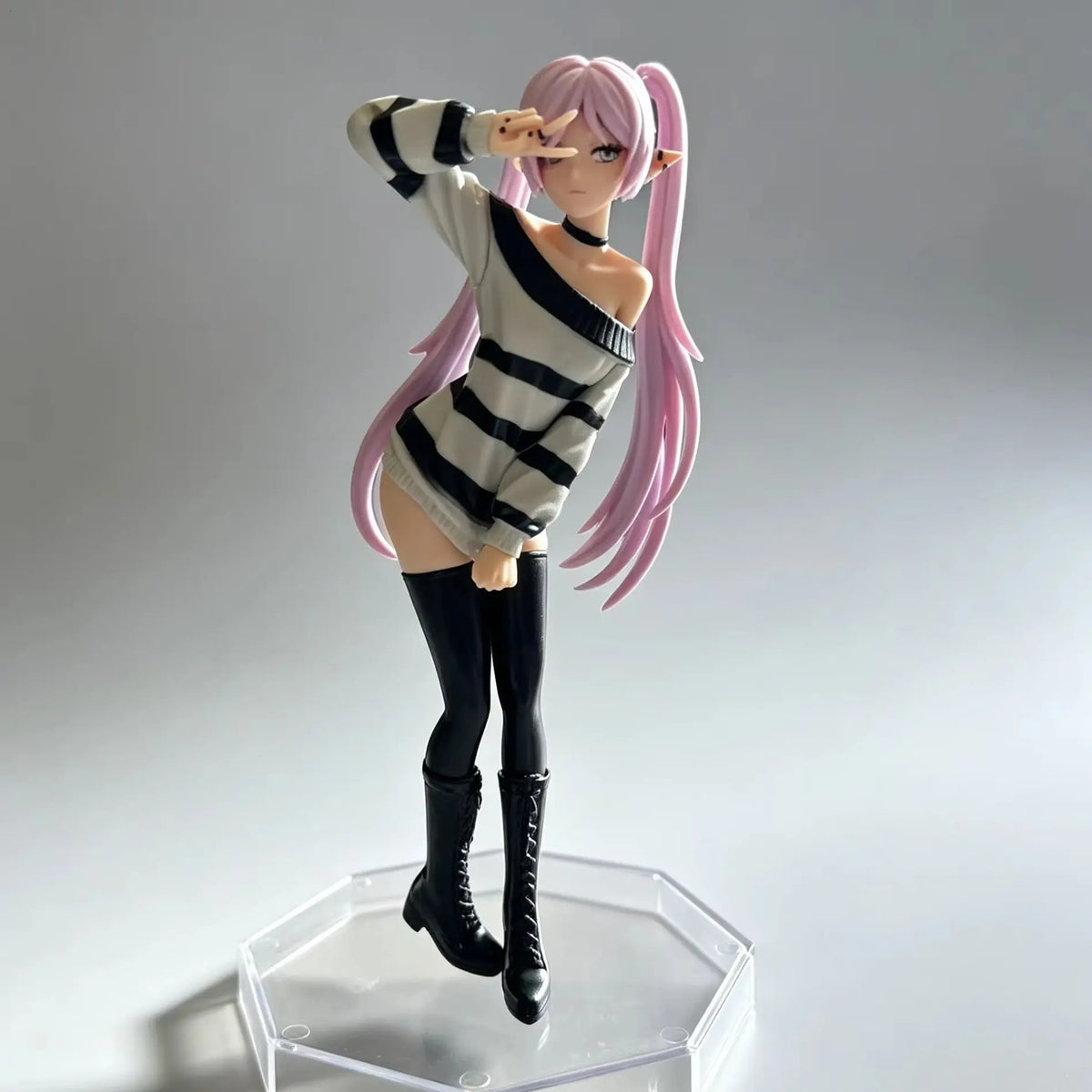 A figurine of an anime-style girl with pink hair wearing a striped sweater and black boots.