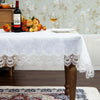 White embroidered lace tablecloth with floral pattern set on a wooden table.