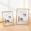 A modern gold picture frame displaying minimalist artwork featuring a vase and an empty chair.