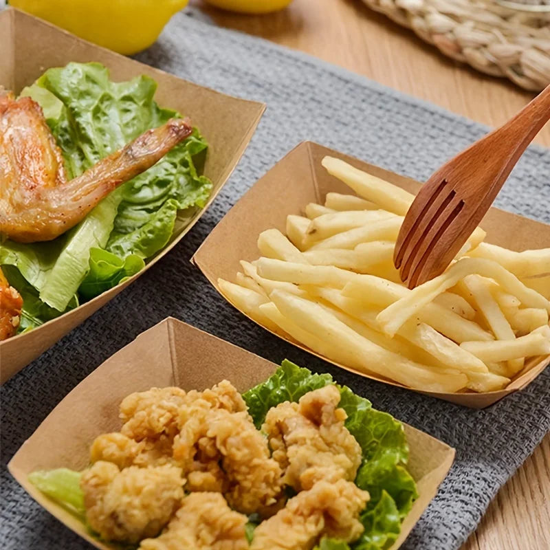 Disposable kraft paper food trays filled with fried chicken and potato wedges served on a gray cloth.