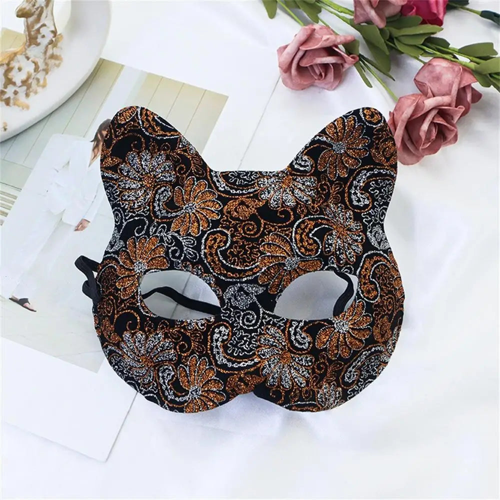 A black and gold patterned lace half-face mask is displayed on a white surface with pink roses.