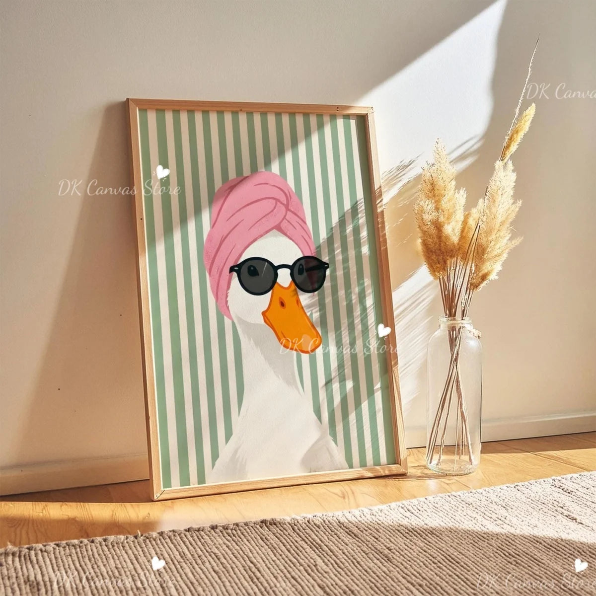 A framed canvas print of a white duck wearing sunglasses and a pink turban, displayed next to dried ornamental grass.