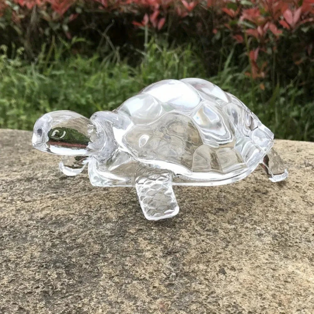 A clear crystal turtle desk ornament resting on a gray stone surface.