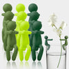 A set of three human-shaped plant supports in shades of green and lime yellow standing upright.