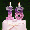 A pink cake decorated with a glitter number 18 candle and a rhinestone crown cake topper.