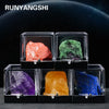 A display of various natural crystal rough stone specimens including pink, green, purple, orange, and blue stones.