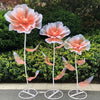 Three large pink and white velvet mesh flowers on metal stands set for wedding decoration