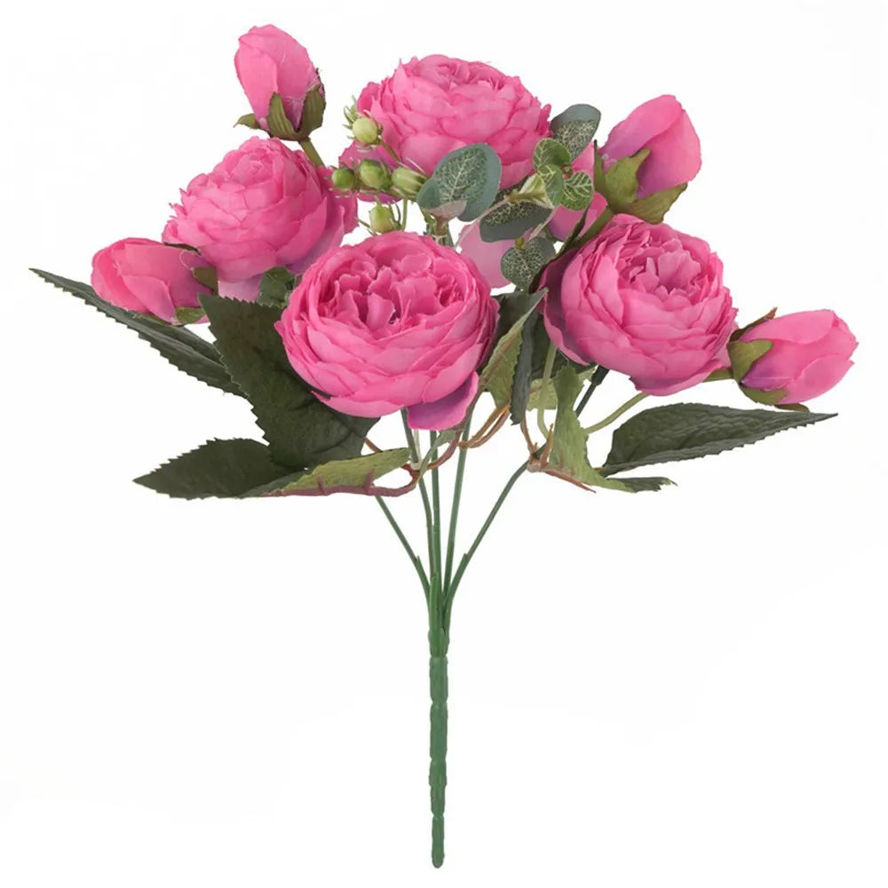 Ein Strauß rosa und magentafarbener künstlicher Seidenrosen und Pfingstrosen mit grünen Blättern