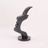A black minimalist side face glasses holder sculpture with an elegant, curved design.