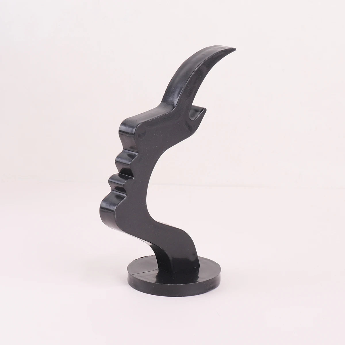 A black minimalist side face glasses holder sculpture with an elegant, curved design.