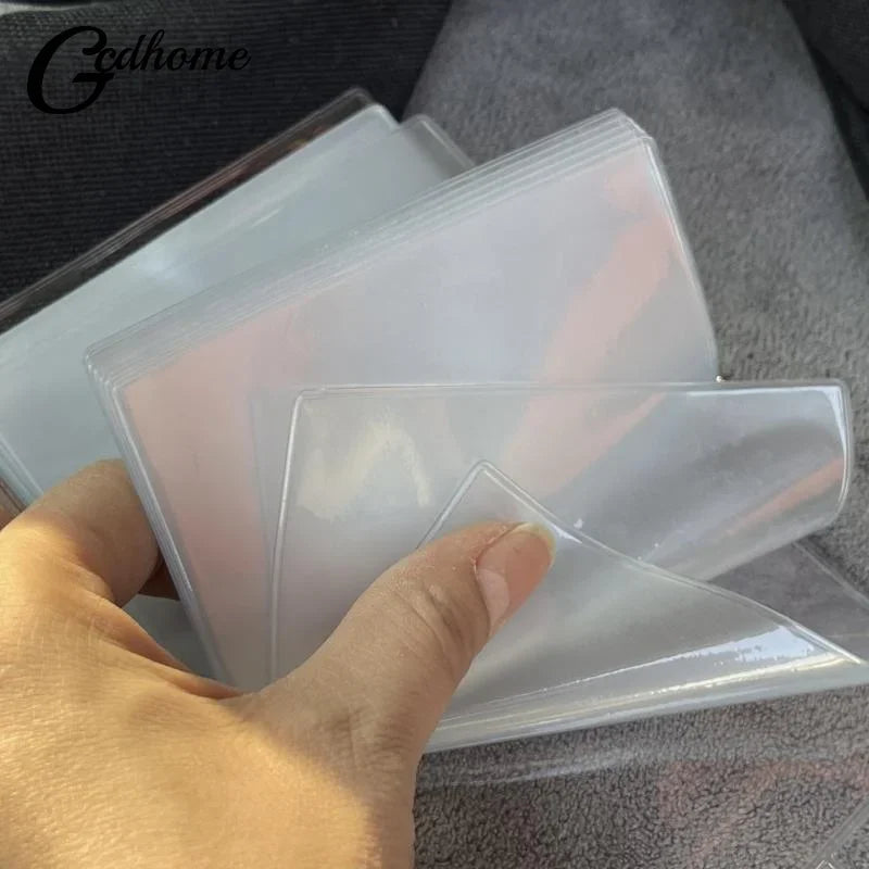 A hand holds a clear plastic photo album with multiple transparent pages for card storage.