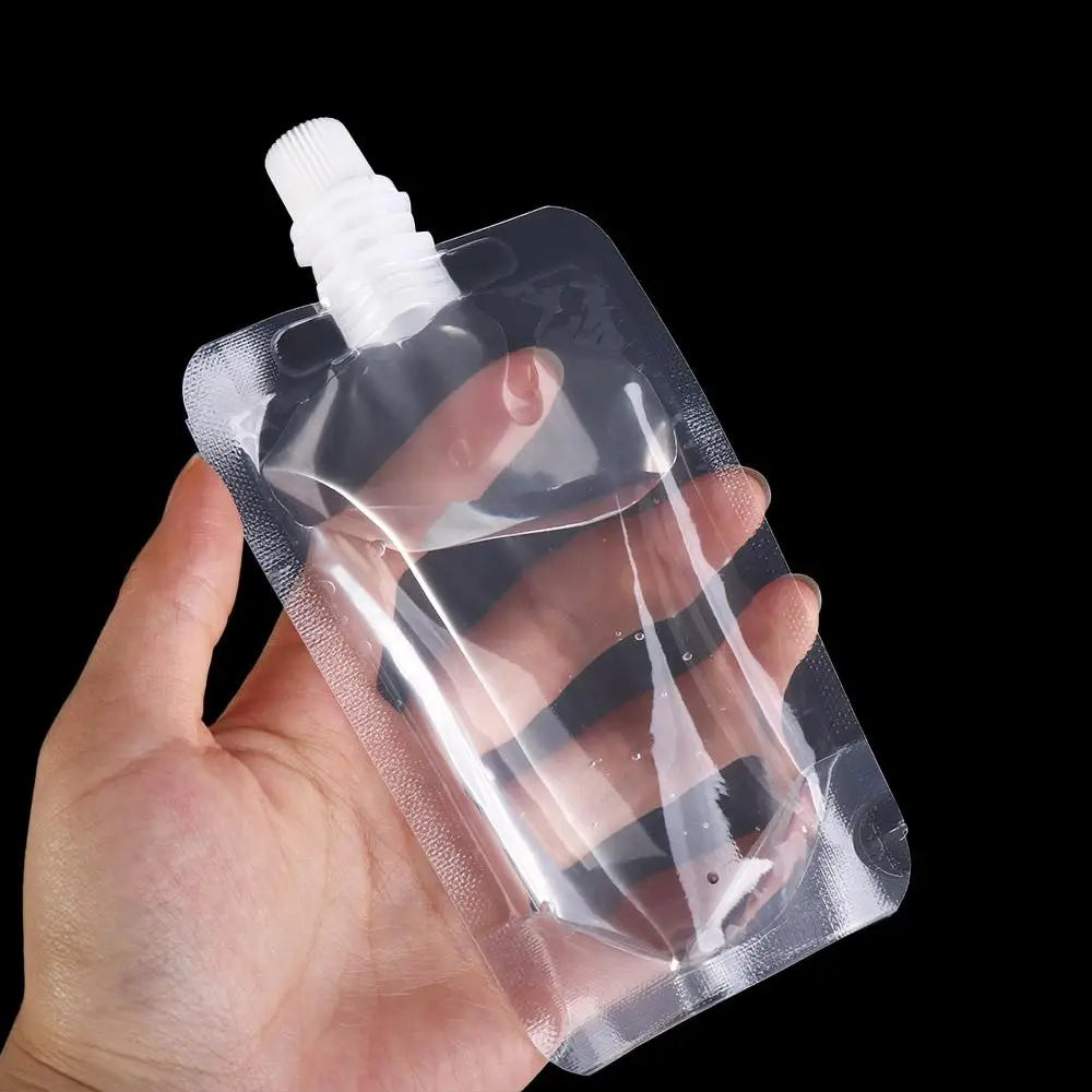 A hand holds a clear, reusable squeezable liquid drink pouch with a white cap against a black background.