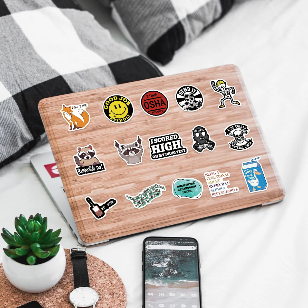 A laptop featuring various funny decals for laptops, bottles, and car surfaces on a wooden background.