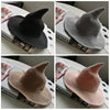 A collection of vintage knit witch hats in black, gray, and pink shades displayed on a white surface.