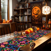A colorful linen table runner with floral patterns is displayed on a wooden table in a home setting.
