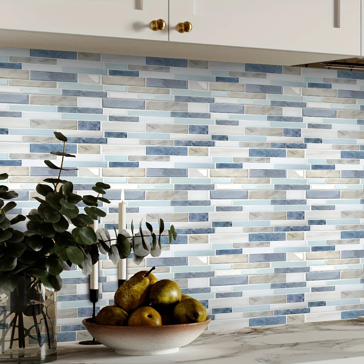 A wall covered in rectangular blue and white marble pattern tiles, with olive fruit and candles in the foreground.