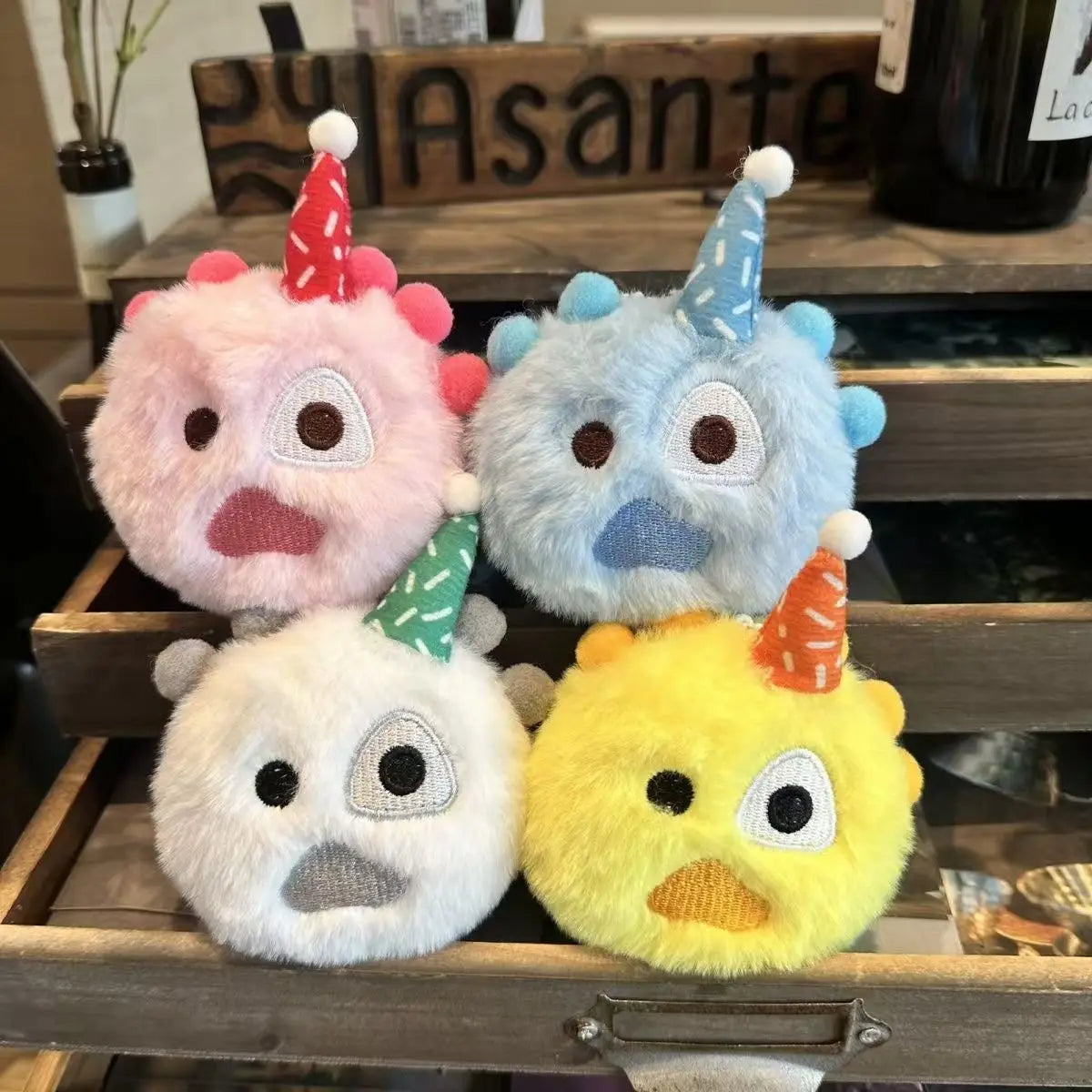 A collection of four fluffy, stylized plush dolls with various colored heads and conical accessories.