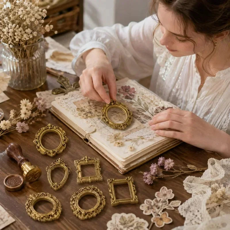 A woman is crafting with a set of vintage gold resin mini photo frames on a wooden surface.