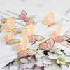 A set of eleven 3D butterfly cake toppers in gold, pink, and purple colors displayed on white paper.