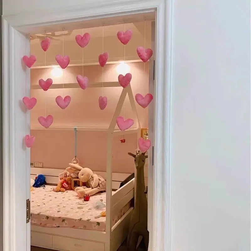 A heart-shaped string door curtain with romantic bead design hangs in a doorway, illuminating a bedroom interior.