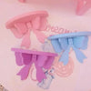 Pink and blue decorative bow-shaped wooden wall shelves displayed on a light pink background.