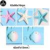 Set of five ocean animal cake toppers including a pink starfish, white starfish, blue starfish, and two seashells.