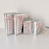 A collection of silver leather photo albums tied with pink ribbon, displayed on a white surface.