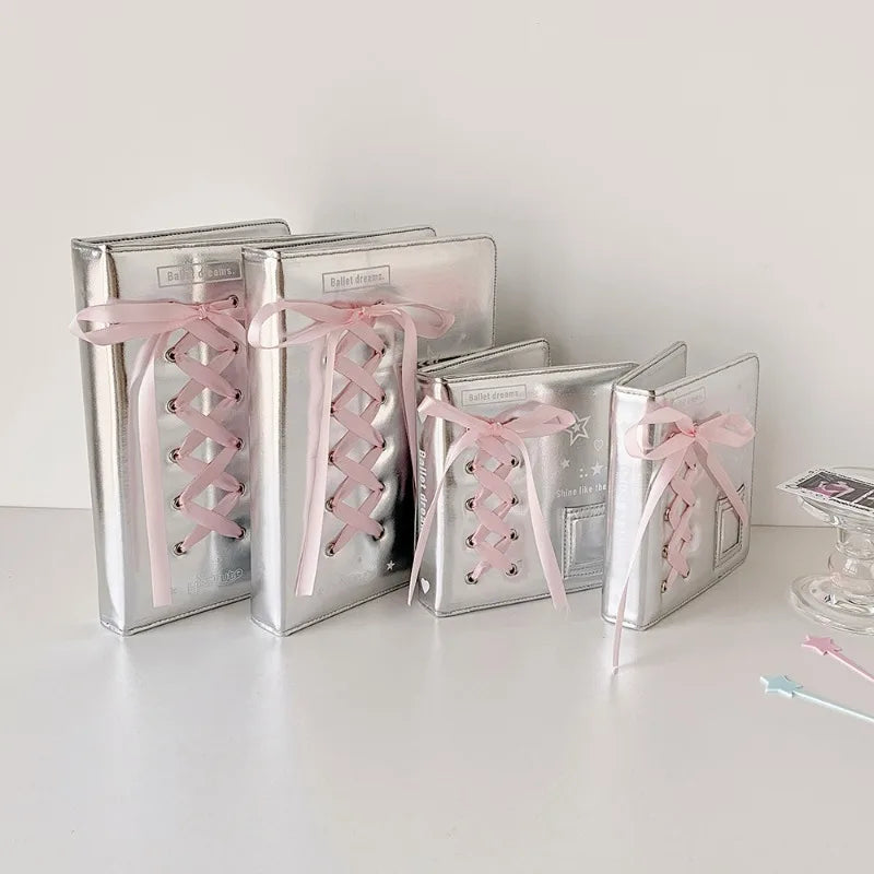 A collection of silver leather photo albums tied with pink ribbon, displayed on a white surface.