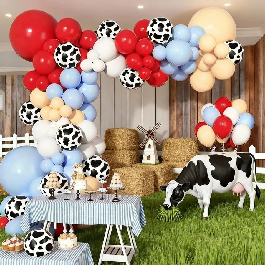 A balloon garland featuring farm animal shapes and colors like red, white, and blue, set against a backdrop of wooden walls a