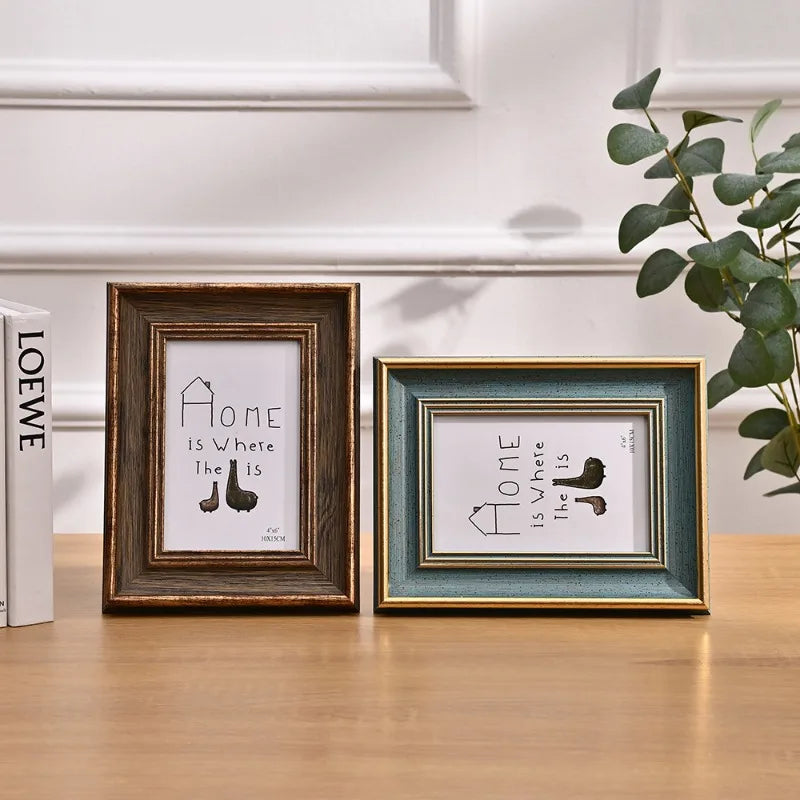 Two wooden photo frames display the text Home Is Where The Is with silhouette icons on a light background.