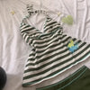 A white and black striped sleeveless top laid flat on a light pink surface.