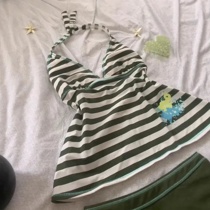 A white and black striped sleeveless top laid flat on a light pink surface.