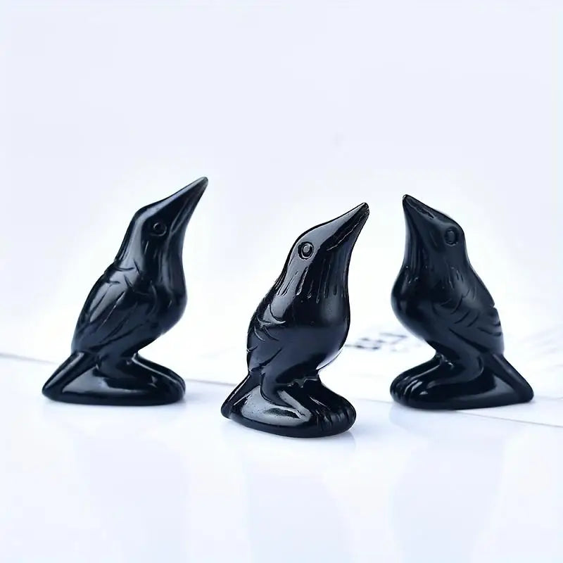 Three handcrafted black obsidian crow statues displayed on a white surface.
