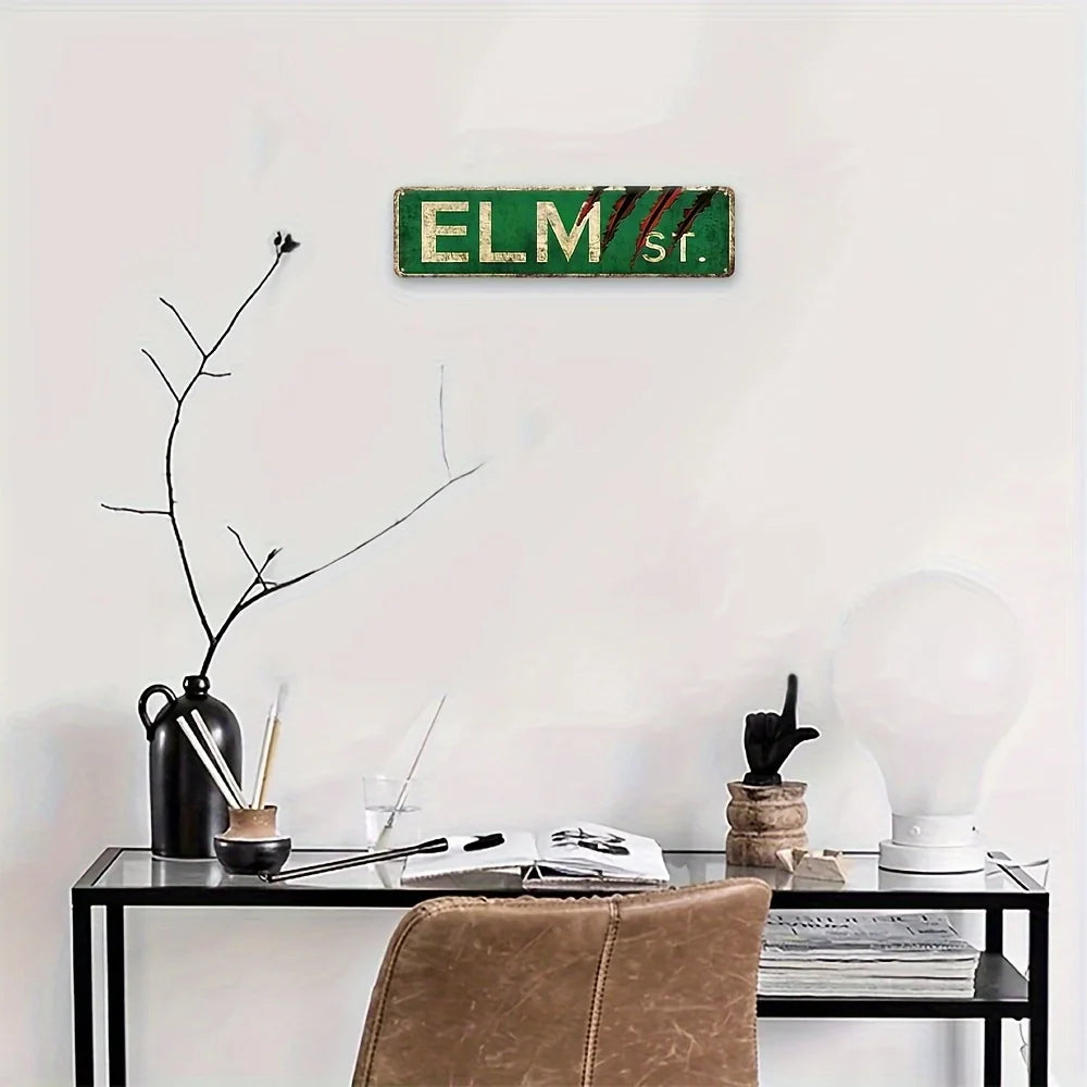 Panneau mural de film d'horreur rustique avec le texte ELM str. en vert et rouge sur un mur blanc.